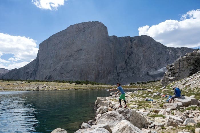 Hooker-120 Mason Earle fishing on a rest day, with the 1,800-foot north wall of Hooker behind. Sendero Luminoso climbs the wall left of the highest poin