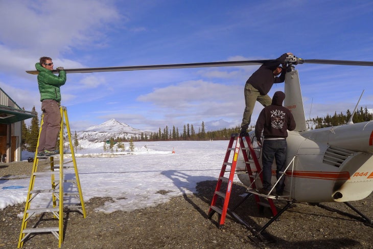 260 Making repairs on the tiny helicopter that ferry the climbers to the mountains. Photo courtesy of Will Sim.