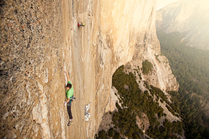 Action_Kevin Jorgeson climbing_(c)CoreyRich Kevin Jorgeson wears a green shirt while climing The Dawn Wall. Multiple portaledges are featured in the background.