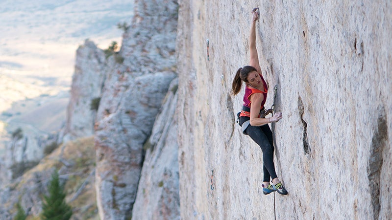 Woman relies on climbing footwear while climbing vertical rock.