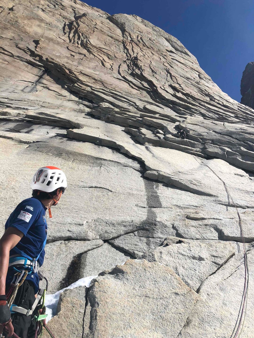 Rock climber ascends a steep mountain face.