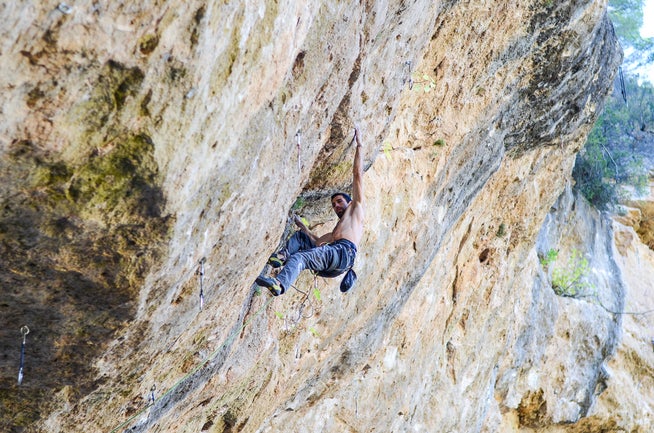 Man climbs steep cliff in Spain.
