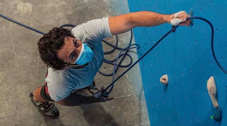 rock climber belaying in gym