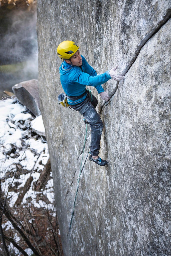 Man climbs rocky cliff in Yosemite National Park.