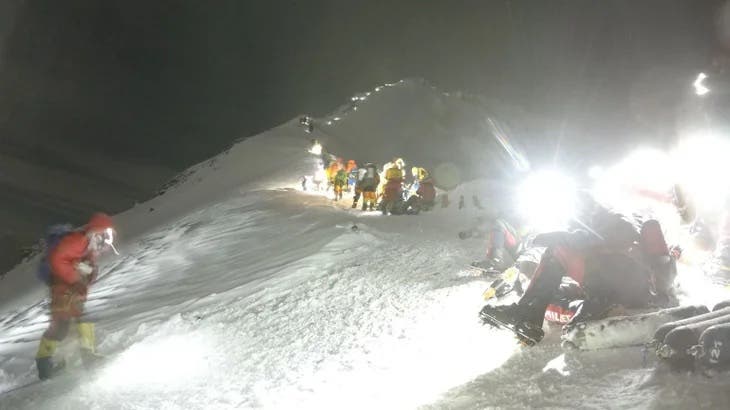 Climbers ascend Mount Everest at night by headlamp.