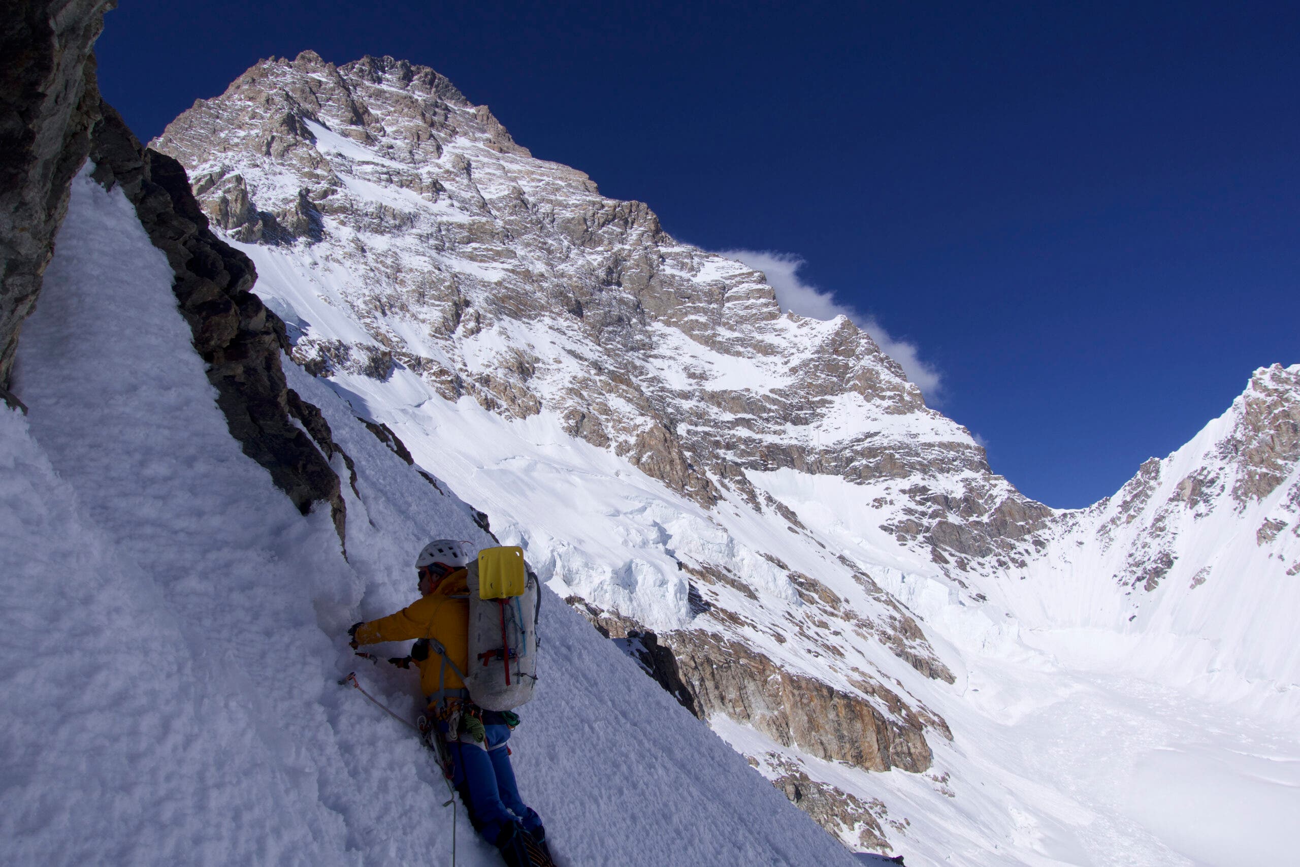An elite alpine climber on a steep snow slope on K2's West Ridge route.