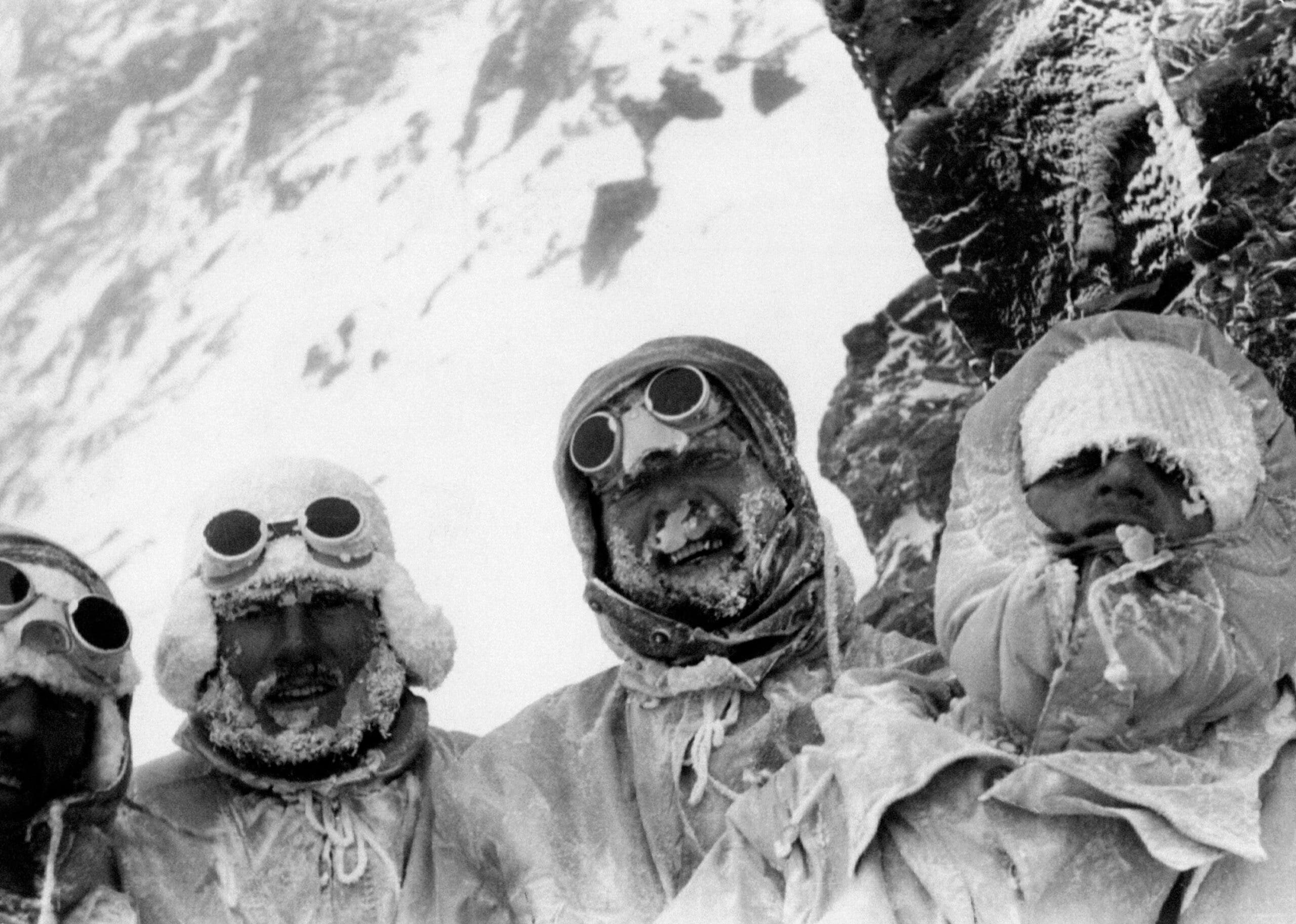 Four K2 members of the 1954 K2 expedition wearing anoraks and trying smile to smile through the ice that has formed on their beards.