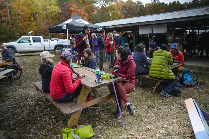 With fall foliage as their backdrop, athletes and festival volunteers eat a breakfast of pancakes and homemade syrup with bacon on the side. Climbers gather around picnic tables wearing brightly colored puffy coats with some navigating to the tables with canes or in a wheelchair.
