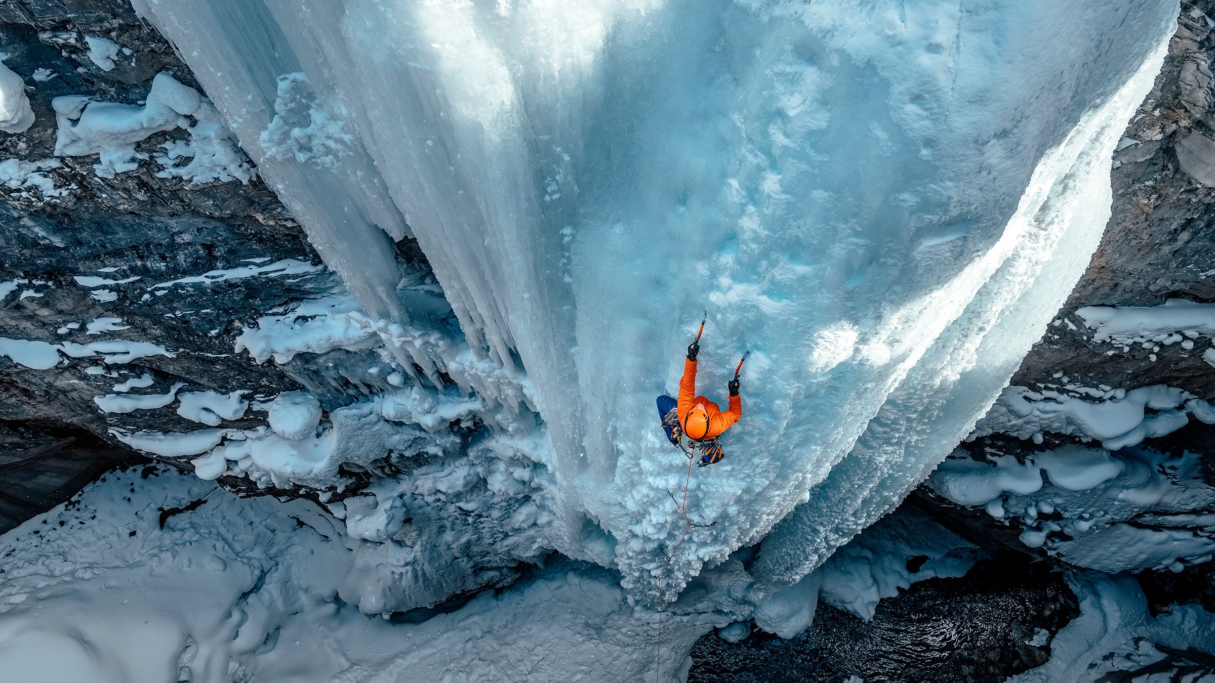 Climber Straps On Crampons To His Mounatineering Boots On Glacier