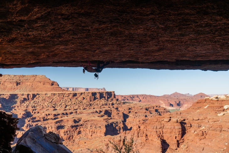 Mary Eden climbs Utah roof crack with view of desert in background.