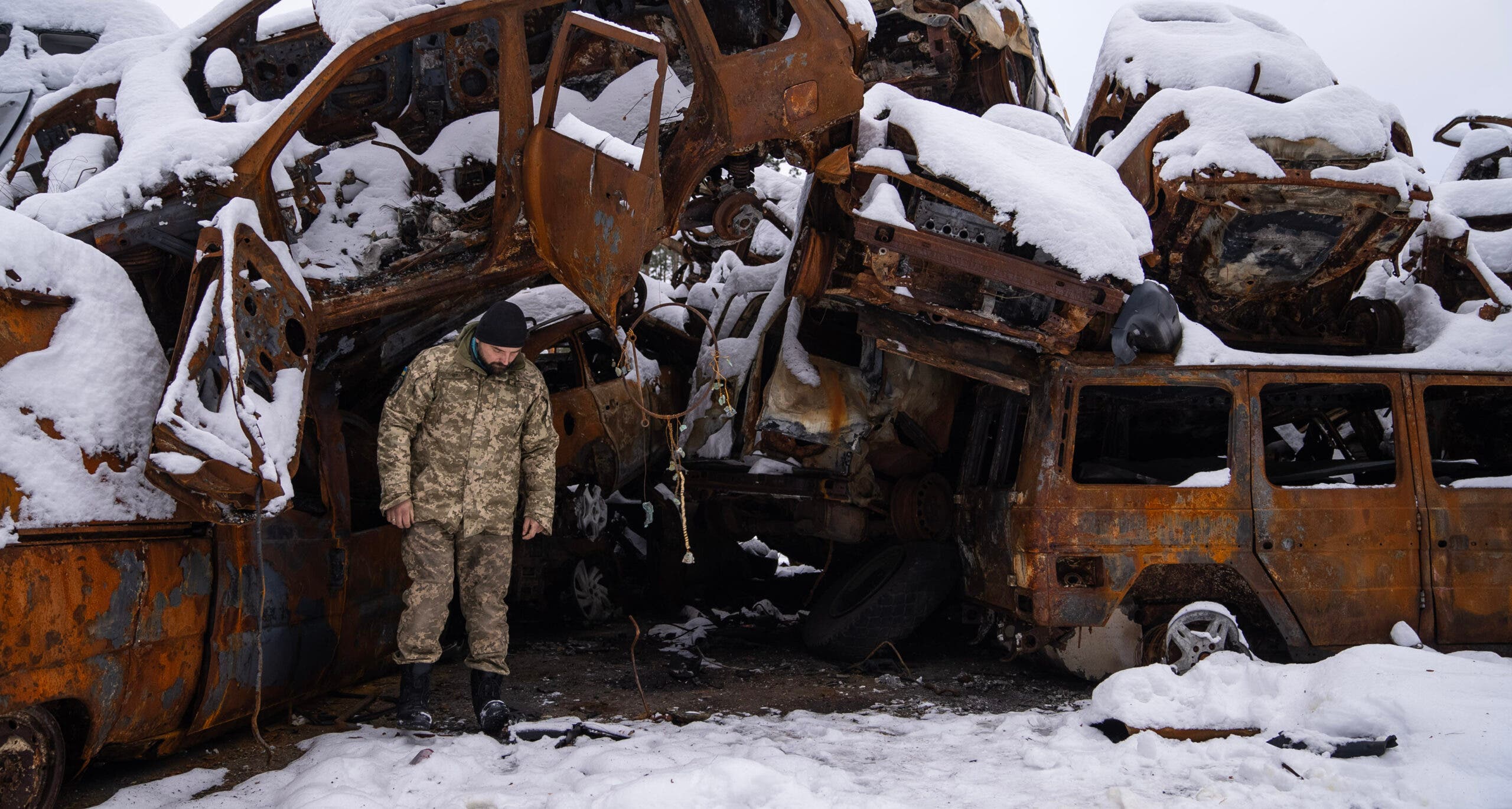 A Ukrainian soldier stands in front of a car cemetary, a memorial to the civilians killed by Russians during the first days of the war.