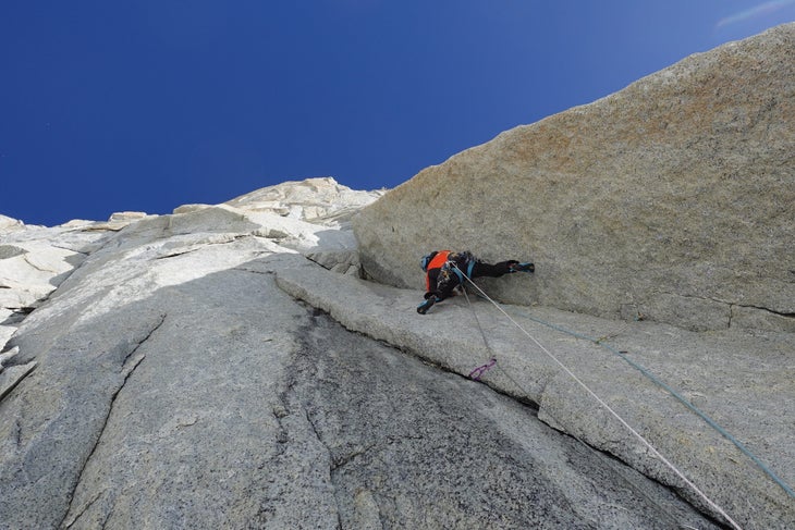 Man climbs a vertical white-granite corner in Patagonia.