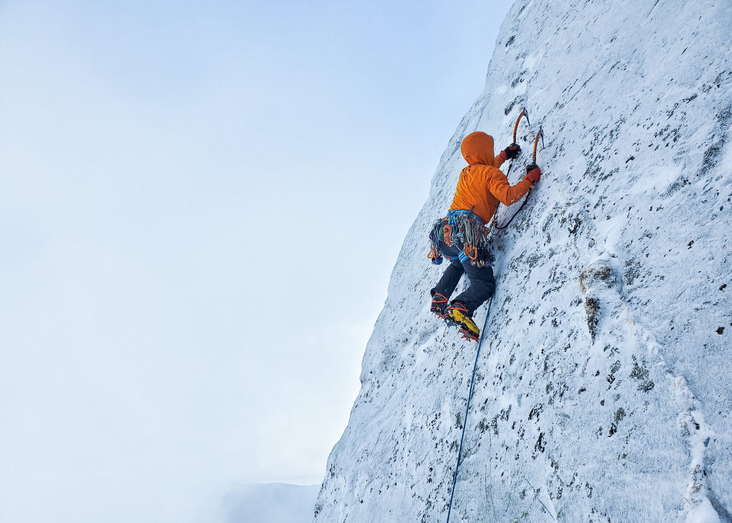 Male climbs slabby, snow-covered rock.