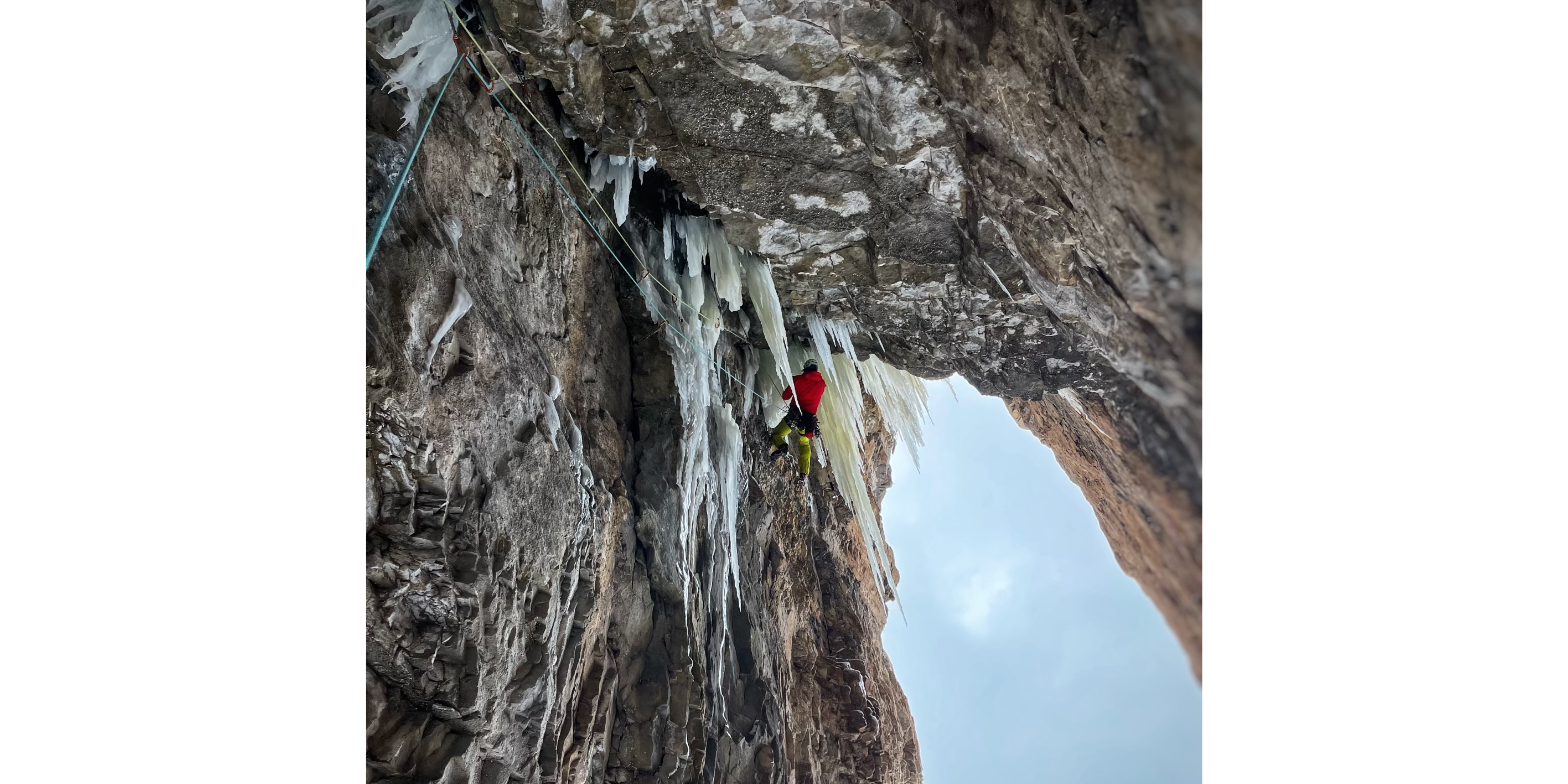 Man traverse beneath a rocky roof dripping with icicles.