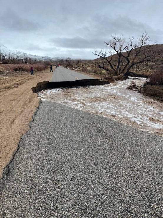 A paved road with a large section of it collapsed due to flooding.