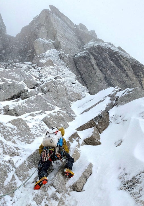 Alpinist climbs snowy mixed terrain on Pigeon Spire, Bugaboos.