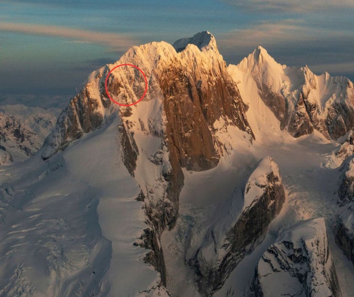 The west side of the Moose's Tooth in Alaska, taken aerially at sunset. A red circular graphic is drawn on the summit ridge to highlight where two climbers went missing.
