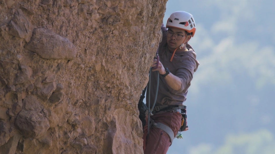 Transgender climber Cat Runner climbs vertical rock arete.