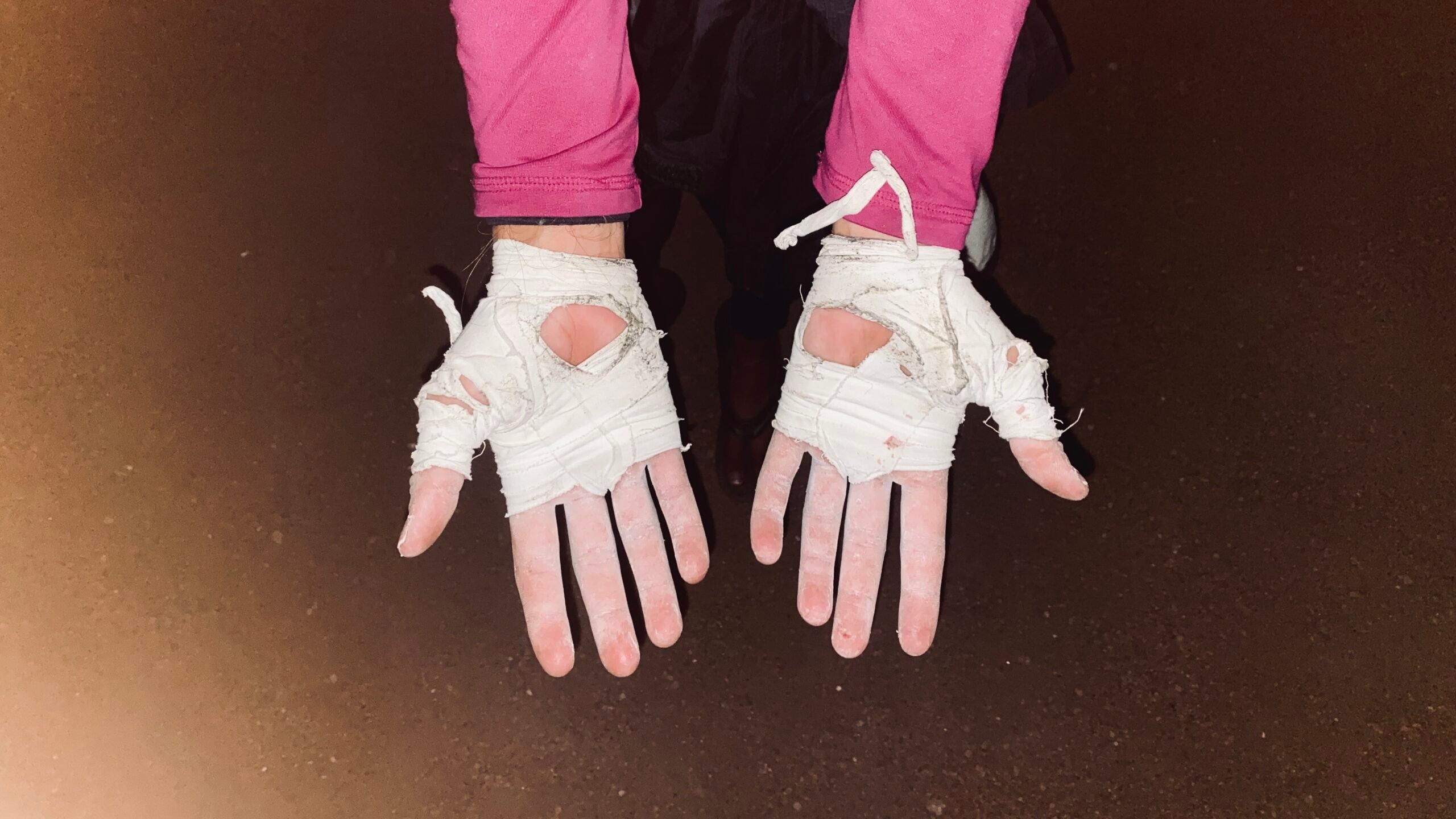 A crack climber holds up her tape gloves, shredded from a full day of use.