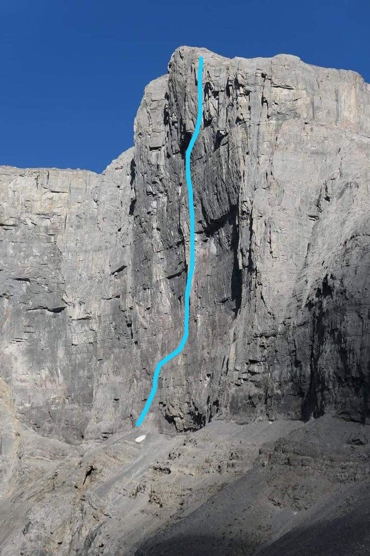 A 1,500 foot limestone cliff in Canada: it's steep, chossy, and dark. It's also got a route map highlighted in blue.