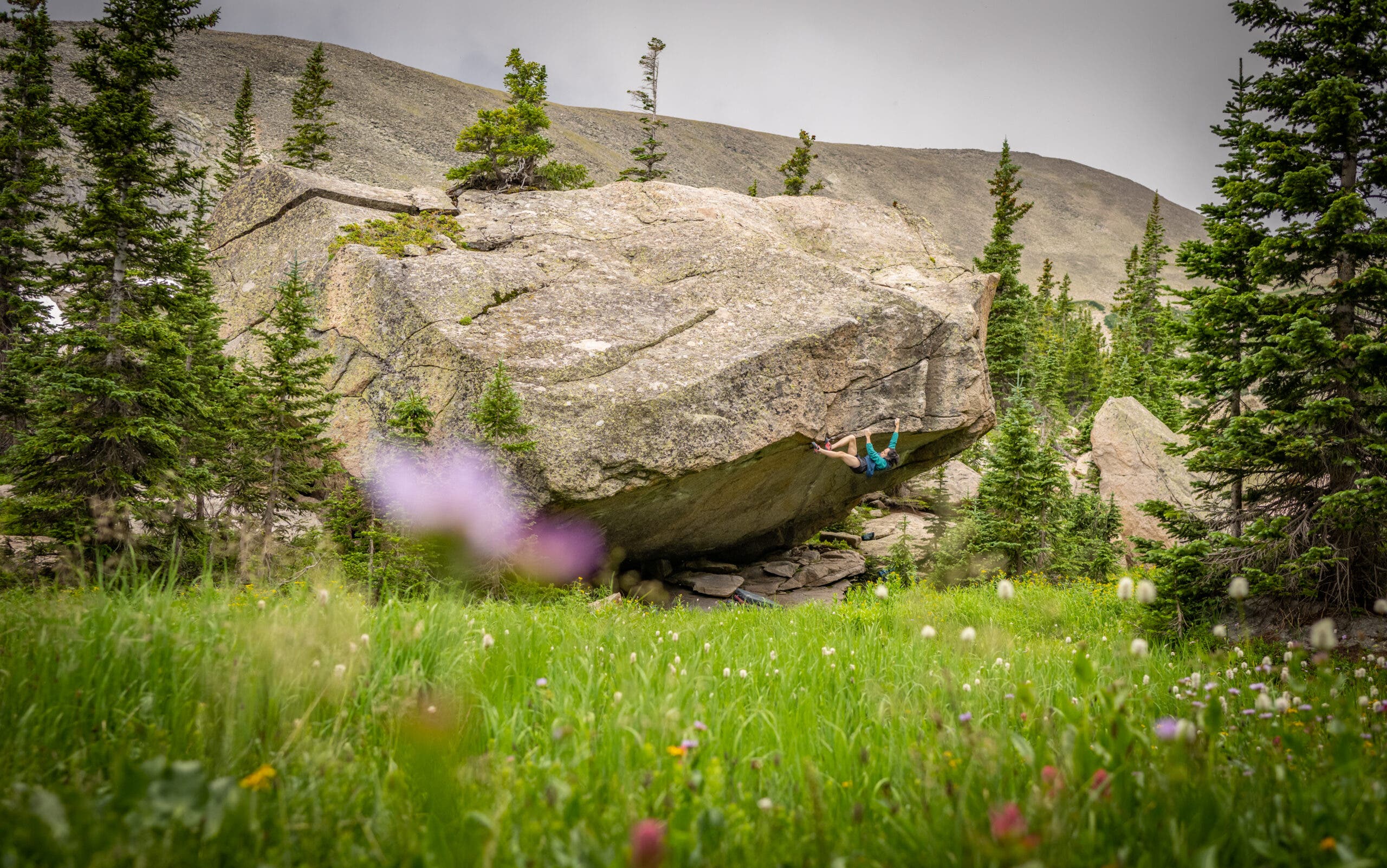 A distance shot of Katie Lamb on the upper section of Box Therapy, showing the green alpine meadow.