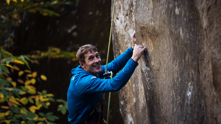 Pearson hanging on a rope from his new route in France, showing how small a pocket is.