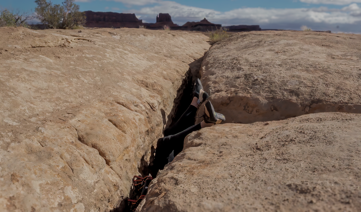 Eden inverted in a roof crack, with her legs visible above the mesa.