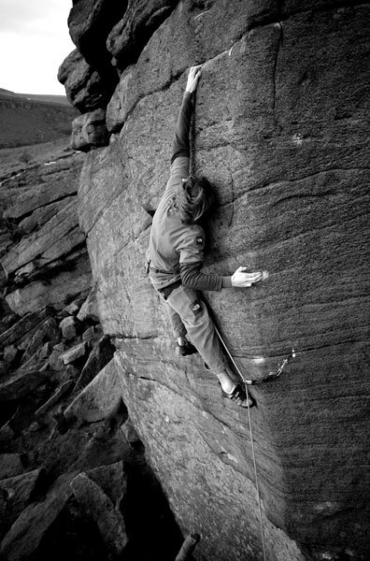 black and white photo of James Pearson on a hard english rock climb called The Promise.