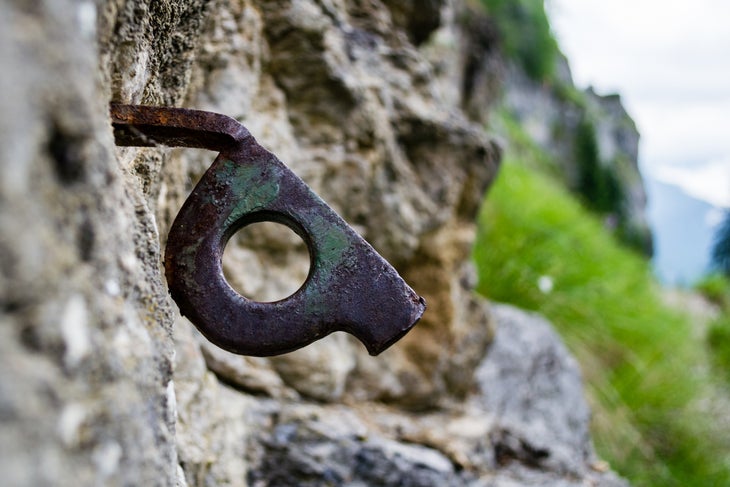 A rusty old piton stuck into a cliff.