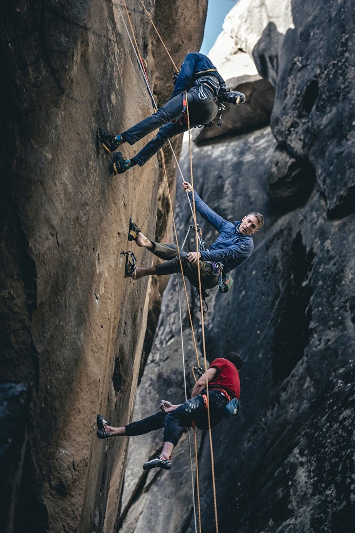 Three people dangling from ropes on Bon Voyage: Adam Ondra, James Pearson, and a cameraperson.