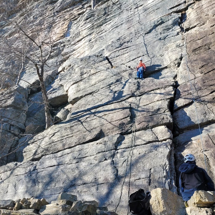 A woman standing on the same ledge from which a climber proposed soloing to the ground after missing a rappel anchor during their descent.