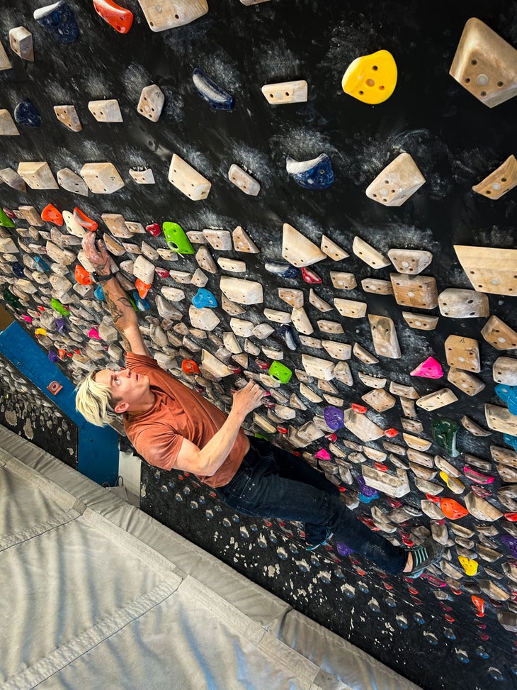 A man climbing on the Woods Board. The photo shows the vast number of and variety of holds on the wall.