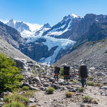 Climbers hiking in Patagonia mountain scape with crash pads on backs