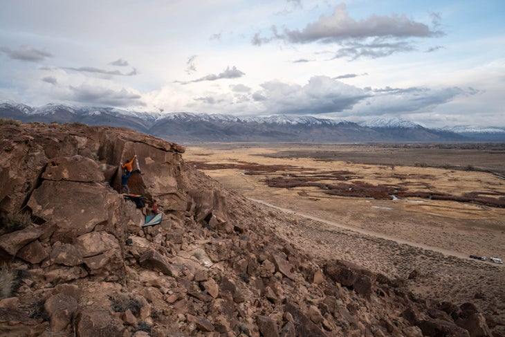 A man climbing a V6 boulder problem in Bishop, California.