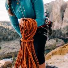 Close up of female climber coiling orange climbing rope