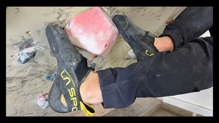 A man doing a bicycle climbing move wearing a pair of Ondra Comps