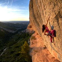 A woman sport climbing at sunset in Margalef, Spain