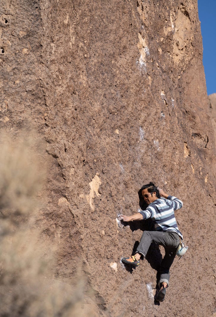 A man in a striped shirt climbing a V3 in Bishop, CA.