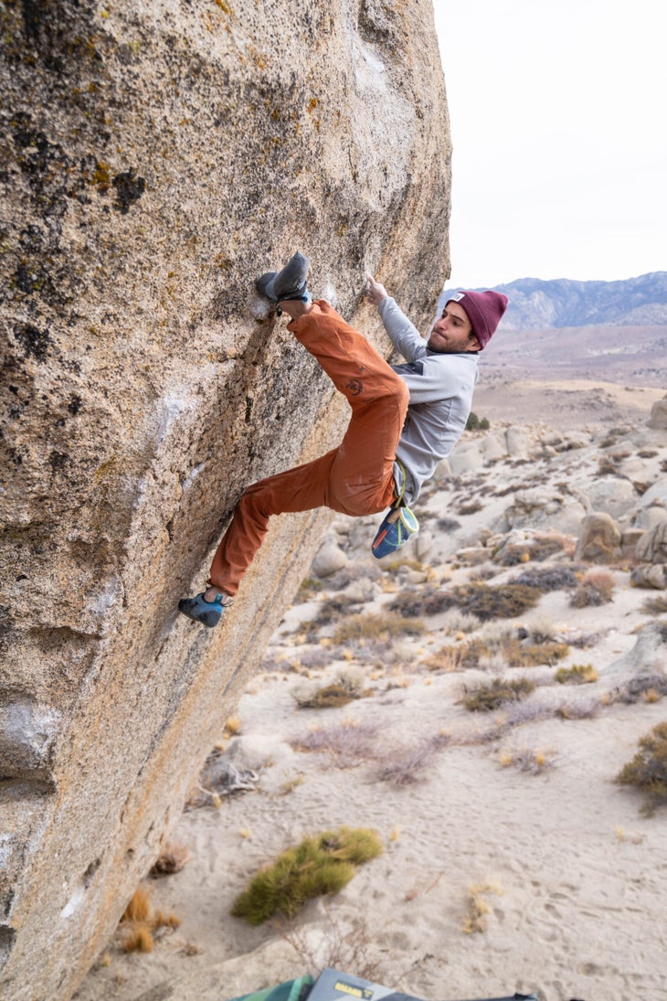 A man committing to a high heel hook on a tall V10 in Bishop, CA.