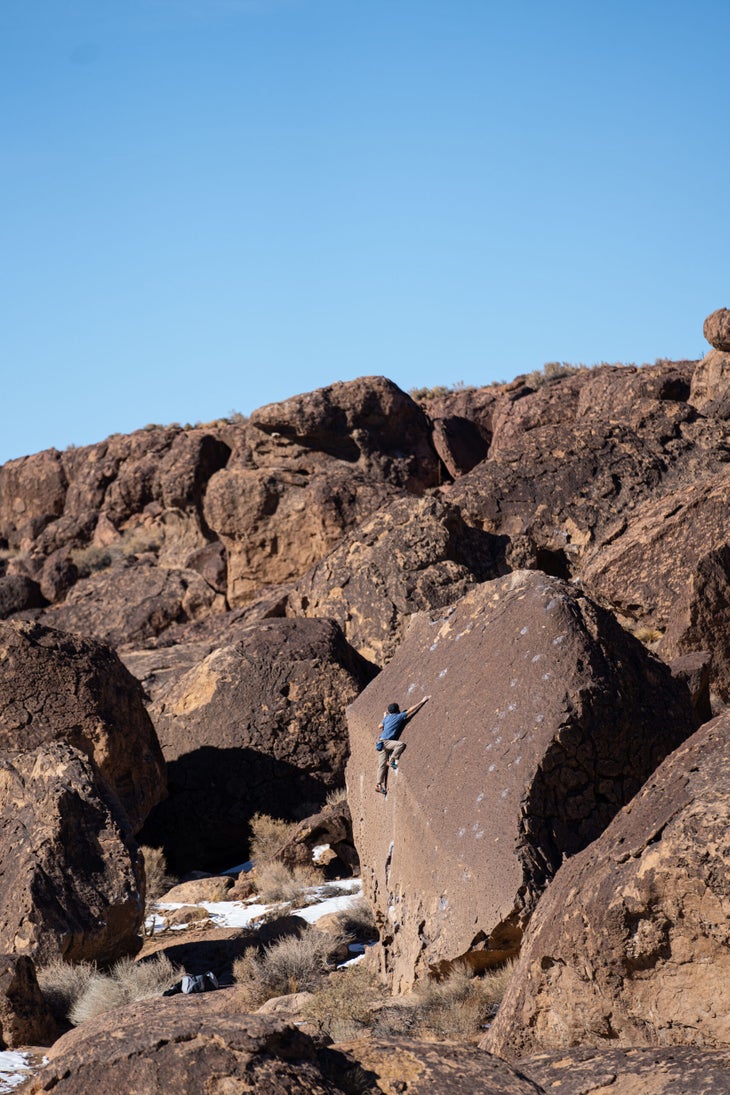 A man climbing a very tall V1 boulder problem in Bishop, California