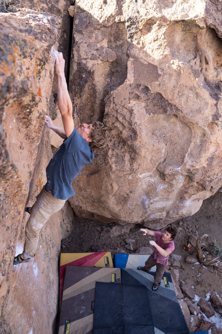 A man trying a highball V5 boulder problem in Bishop