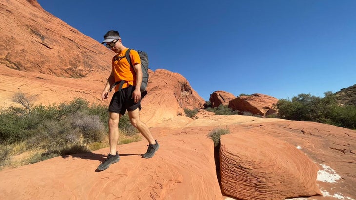 Man wearing approach shoes hiking through rocky desert landscape