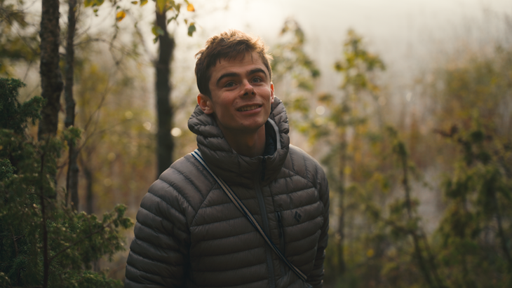 A portrait of professional rock climber Jim Pope standing in an autumnal forest. Pope is a frequent star on Sam Lawson's Wedge YouTube channel.