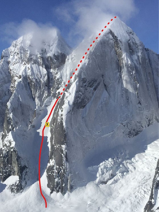 Image of a snow-covered granite peak with a red route line drawn on it. A yellow X appears on a steep snow field a third of the way up the red line.