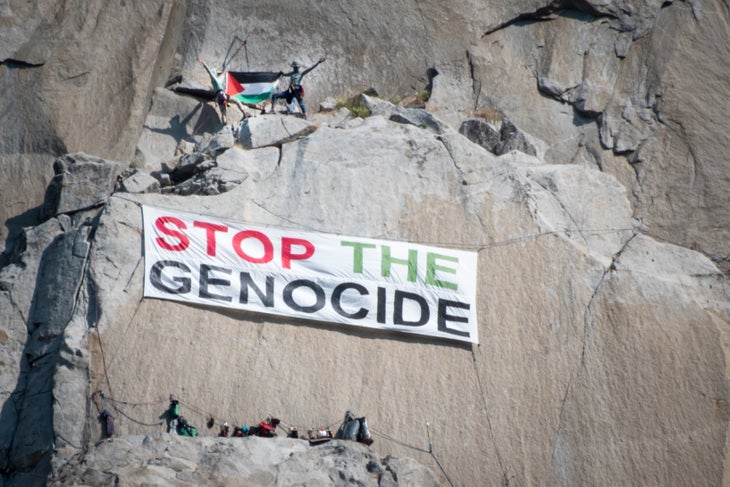 An image of the "Stop the Genocide" as seen from the floor of Yosemite Valley. Above them, two climbers hold a Palestinian flag.