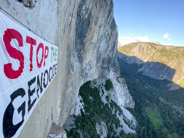 An image of the "stop the genocide sign" taken from the climber's perspective on the wall—with a view of Yosemite Valley below
