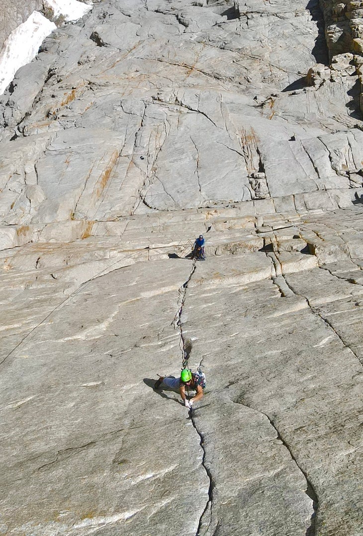 A climber in a green helmet on the crux pitch of Keel Haul.