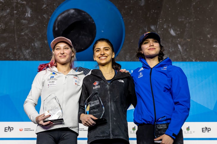 Three female competition climbing rivals smiling on a World Cup podium