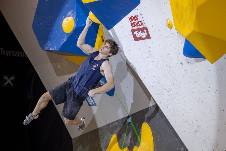 Colin Duffy hanging from one bent arm during a bouldering competition