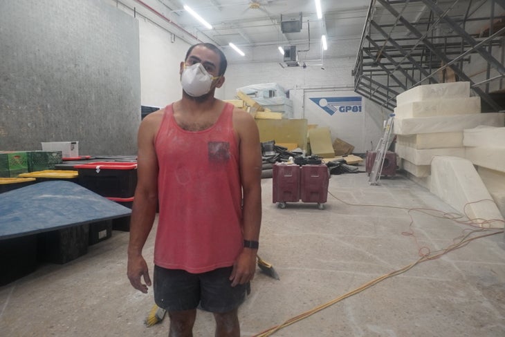 A man wearing a ventilation mask dismantling GP81's old climbing gym space